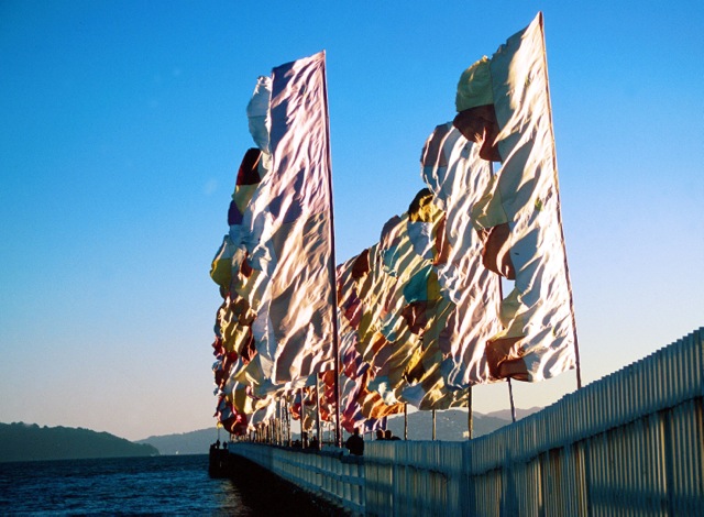"These large flags are called “Living Standards”. They were originally commissioned by the Cornish Tate Gallery to celebrate the solar eclipse of 1999. Working in conjunction with the St Ives International organization and the local councils. The flags were designed to work with the exceptional winds coming off the Atlantic. Using a subtle blend of pastel shades, they were conceived to be a roaming program, appearing at three locations over three weeks in West Penwith, Cornwall. Subsequently, the flags went on to New Zealand, again roaming three locations. The final outing for the “Living Standards” flags, was on the island of Terscelling in the Netherlands, as part of the Oerol Festival." From anguswatt.net