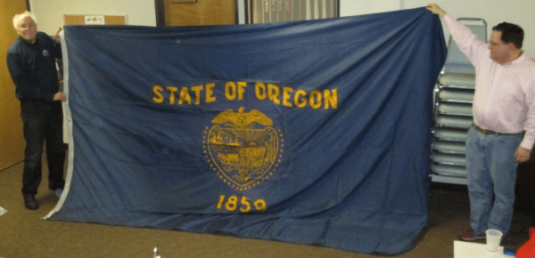 Michael Orelove and Scott Mainwaring stretch out an 8' x 12' Oregon state flag.