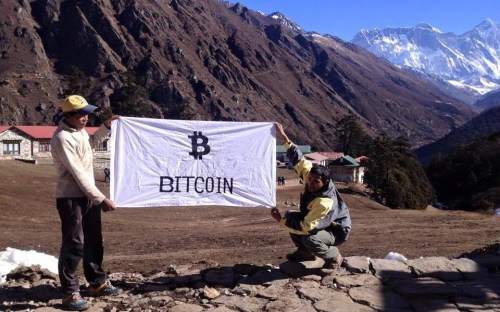 Allex Ferreira, a "Brazilian Bitcoin enthusiast" poses with a Bitcoin flag he plans to unfurl on the summit of Mt. Everest.  From cryptohoot.com.