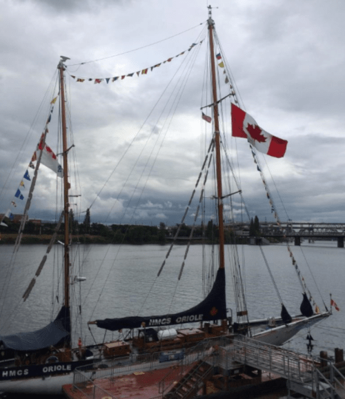 A large Maple Leaf Flag, along with many smaller flags, flies from the sailing ketch HMCS Oriole, a Canadian Navy sail training vessel (launched in 1921, she is the oldest commissioned ship in the Royal Canadian Navy).