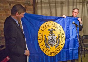 Portland City Councilor Ed Suslovic presenting the flag of the City of Portland